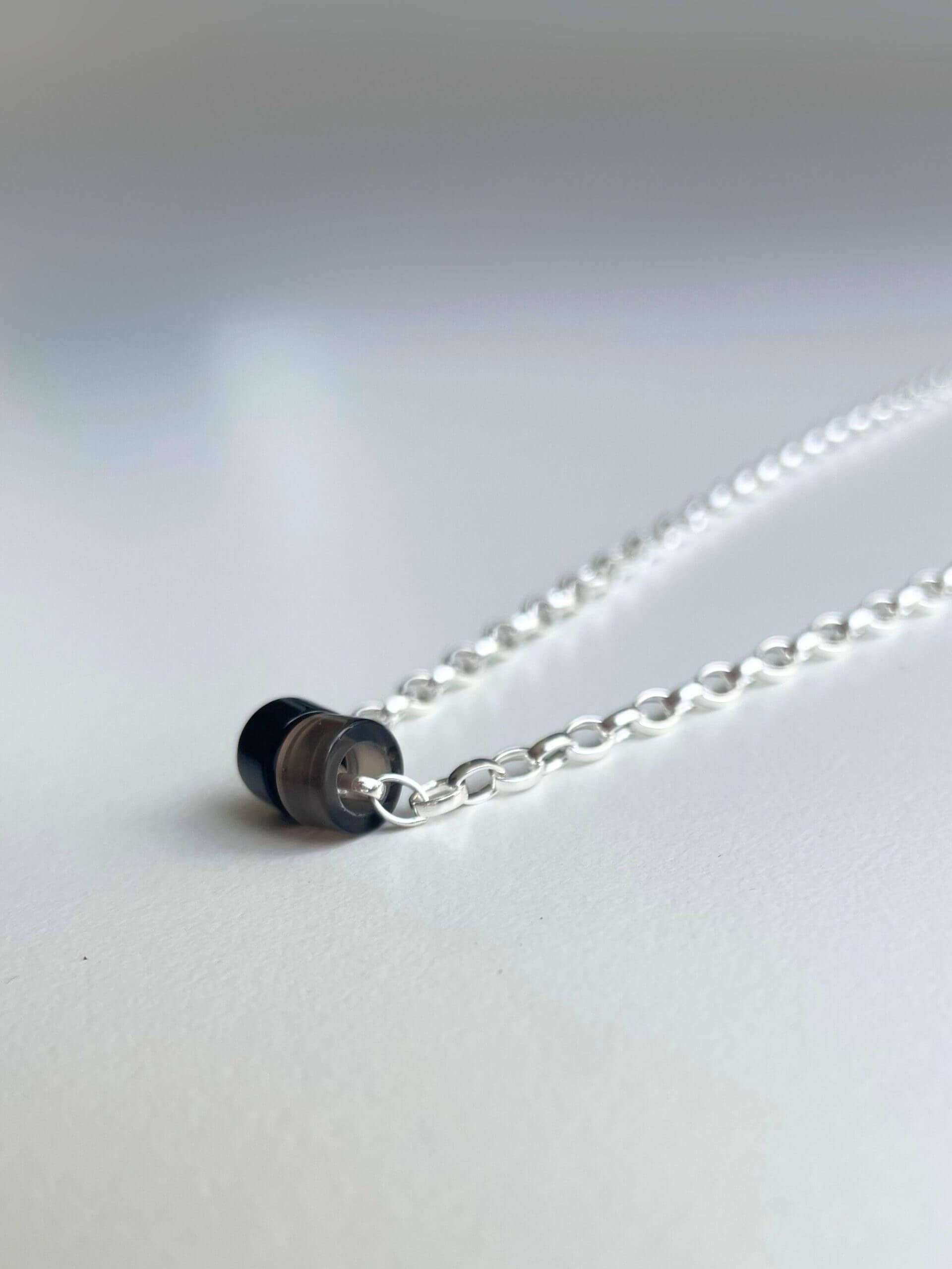 „Timeless sterling silver necklace, 48 cm length, adjustable to 46 cm and 44 cm, with two crystal donut pendants in onyx and smoky quartz; handcrafted from recycled materials, symbolizing grounding, clarity, and transformation.“