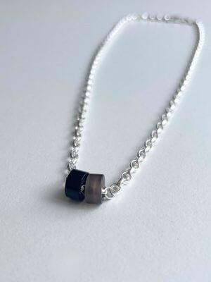 „Timeless sterling silver necklace, 48 cm length, adjustable to 46 cm and 44 cm, with two crystal donut pendants in onyx and smoky quartz; handcrafted from recycled materials, symbolizing grounding, clarity, and transformation.“