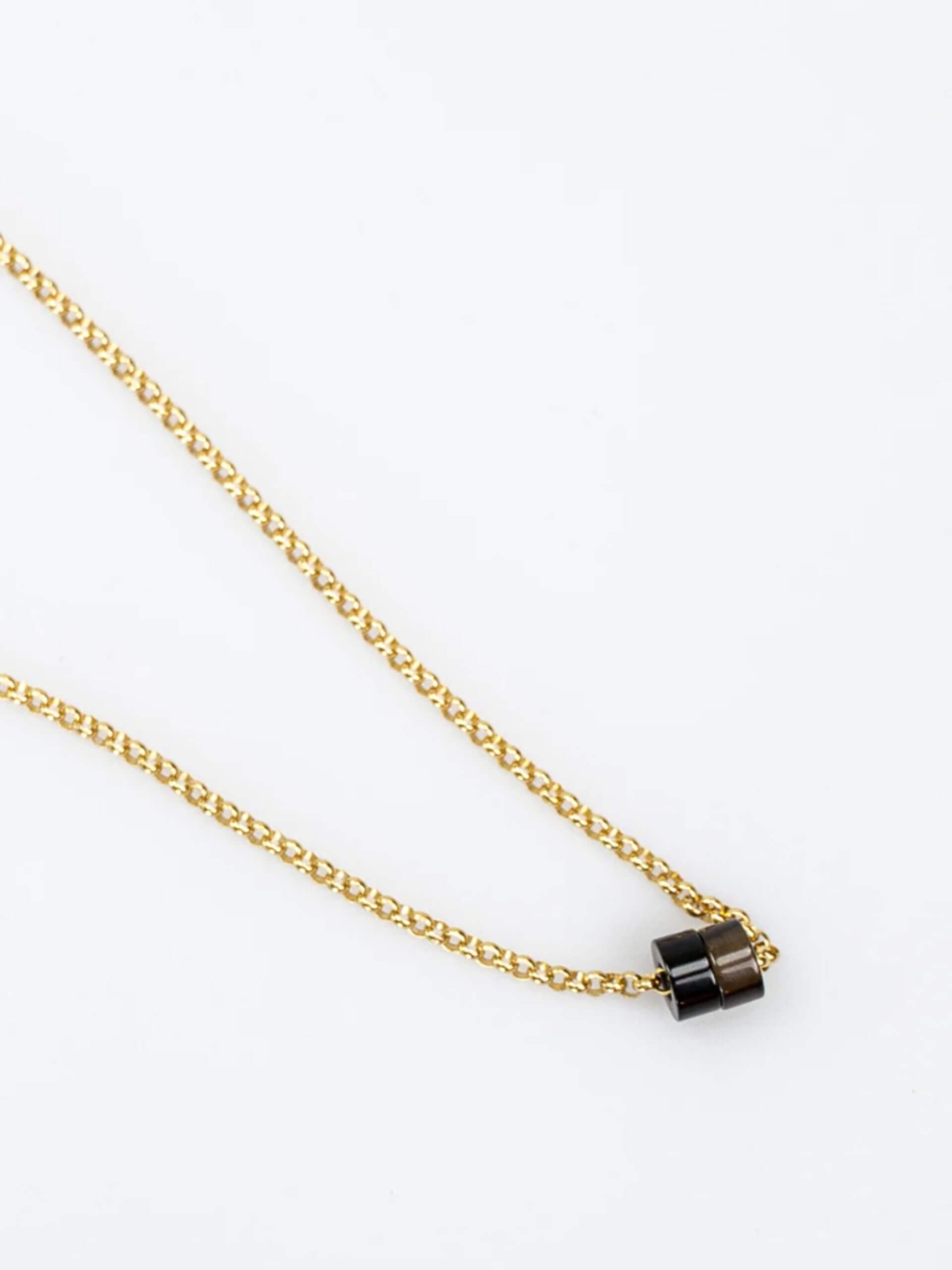 „Timeless 18K gold-plated sterling silver necklace, 48 cm length, adjustable to 46 cm and 44 cm, with two crystal donut pendants in onyx and smoky quartz; handcrafted from recycled materials, symbolizing grounding, clarity, and transformation.“
