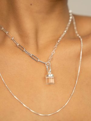 Close-up of a sterling silver necklace with a single chain, featuring a clear quartz charm and a sleek silver clip designed for interchangeable crystal charms.