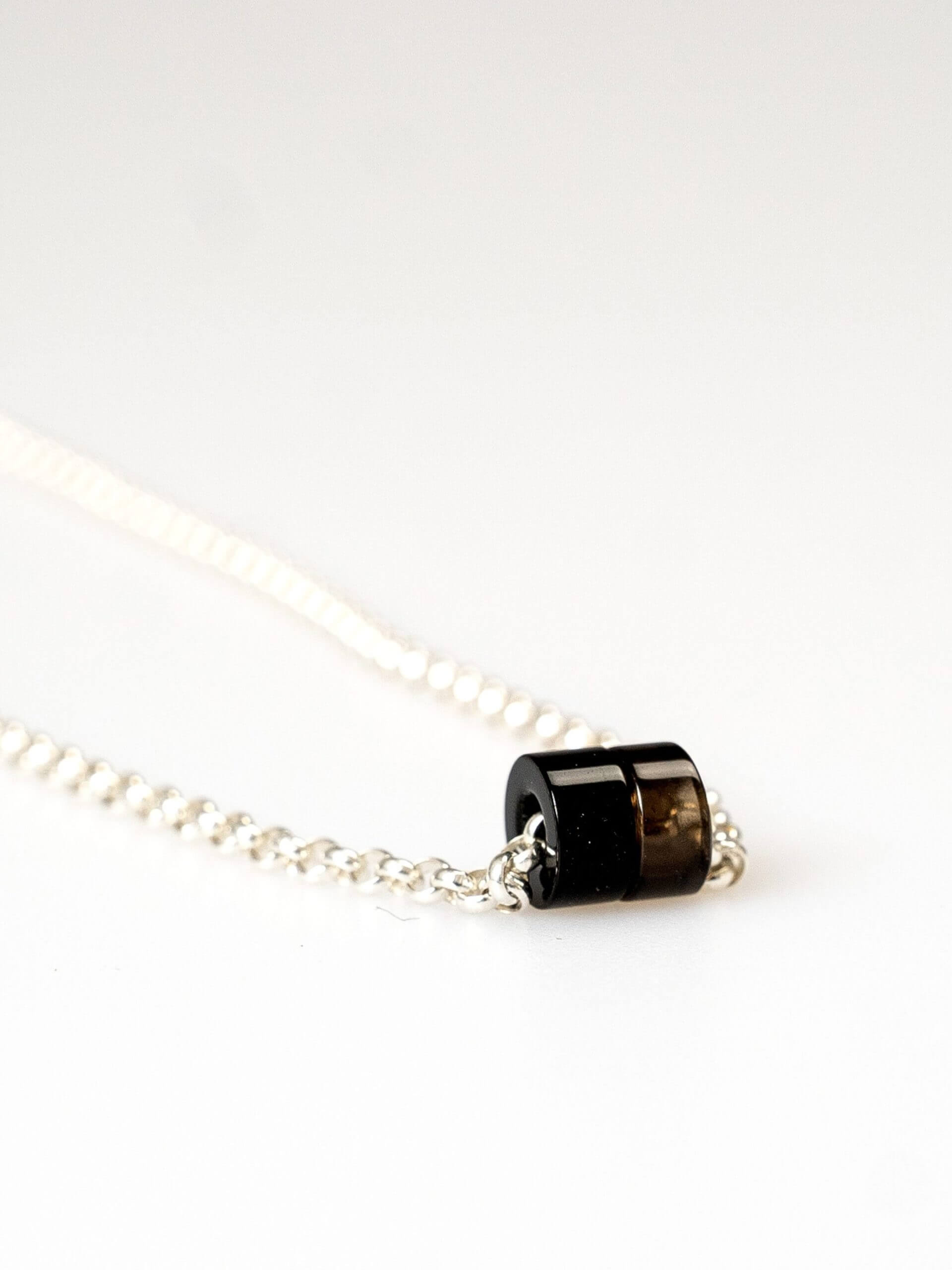 „Timeless sterling silver necklace, 48 cm length, adjustable to 46 cm and 44 cm, with two crystal donut pendants in onyx and smoky quartz; handcrafted from recycled materials, symbolizing grounding, clarity, and transformation.“